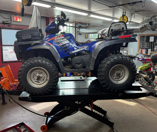 Blue 500cc ATV on a service lift in a repair shop, all-terrain vehicle maintenance