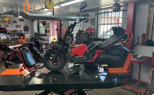Red and black scooter with open seat under repair in mechanic workshop