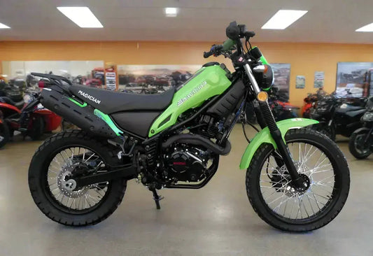 Green Magician dirt bike with knobby tires displayed in indoor showroom