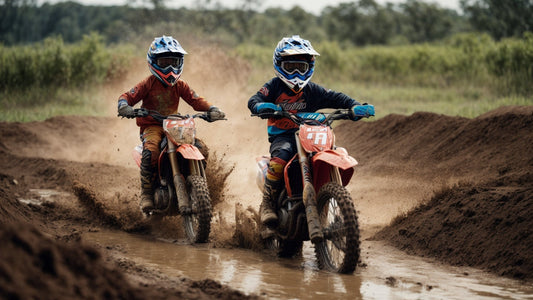 Two kids in helmets riding dirt bikes through muddy trail splashing water on off-road track