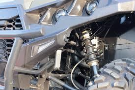 Close-up of ATV suspension, wheel, and headlights in a repair shop setting