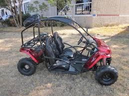 Red two-seater go-kart with roll cage parked outdoors on grass