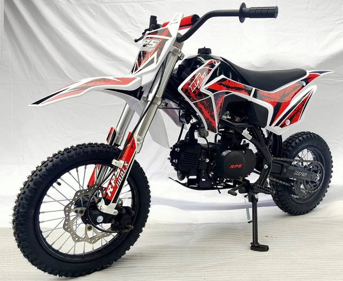 Red and black youth dirt bike with knobby tires and motocross graphics on white background
