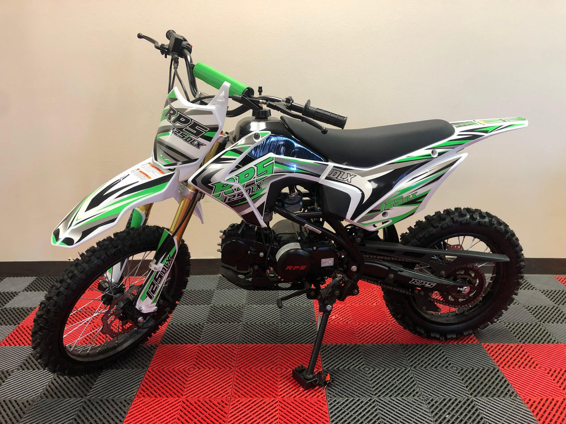RPS 125DLX youth dirt bike with black seat and green white black graphic design on red and black floor