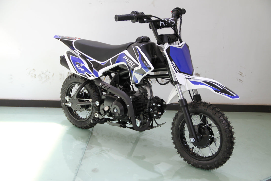 Blue and white youth dirt bike with off-road tires and black seat on a smooth floor against a white wall