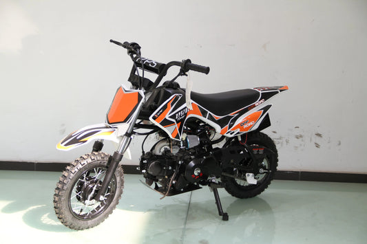 Youth off-road dirt bike with orange, black, and white graphics on a showroom floor