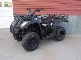 Black 4-wheeler ATV parked on concrete, utility racks, outdoor setting, all-terrain vehicle
