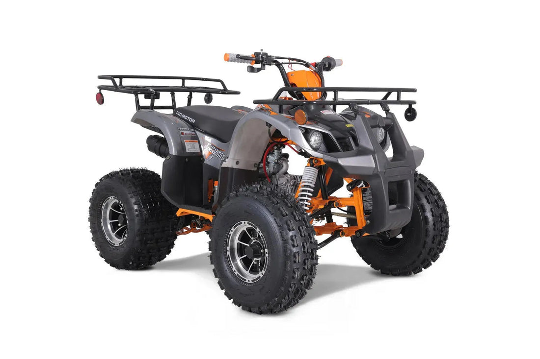 Dark gray and orange ATV with rugged tires, front rack, and off-road suspension on white background