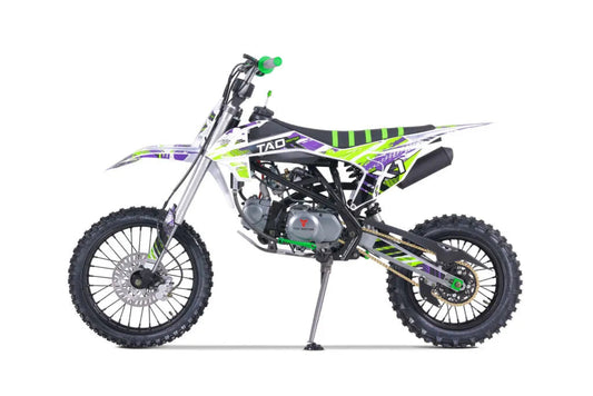 Side view of a white, green, and purple off-road dirt bike with knobby tires and sporty graphics