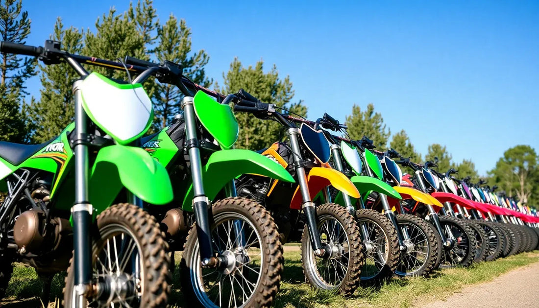Row of colorful dirt bikes with knobby tires lined up outdoors on grass under blue sky
