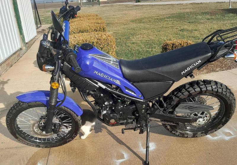 Blue 250cc enduro dirt bike with off-road tires parked on pavement outdoors