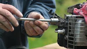 Mechanic repairing small engine with socket wrench, outdoor power equipment service