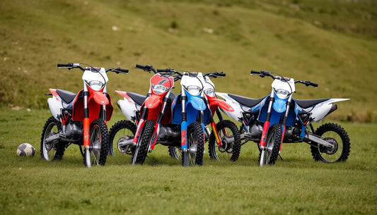 Four colorful dirt bikes parked on grassy field outdoors, motocross off-road motorcycles
