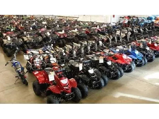 Indoor showroom with rows of kids and adult ATVs and dirt bikes in various colors