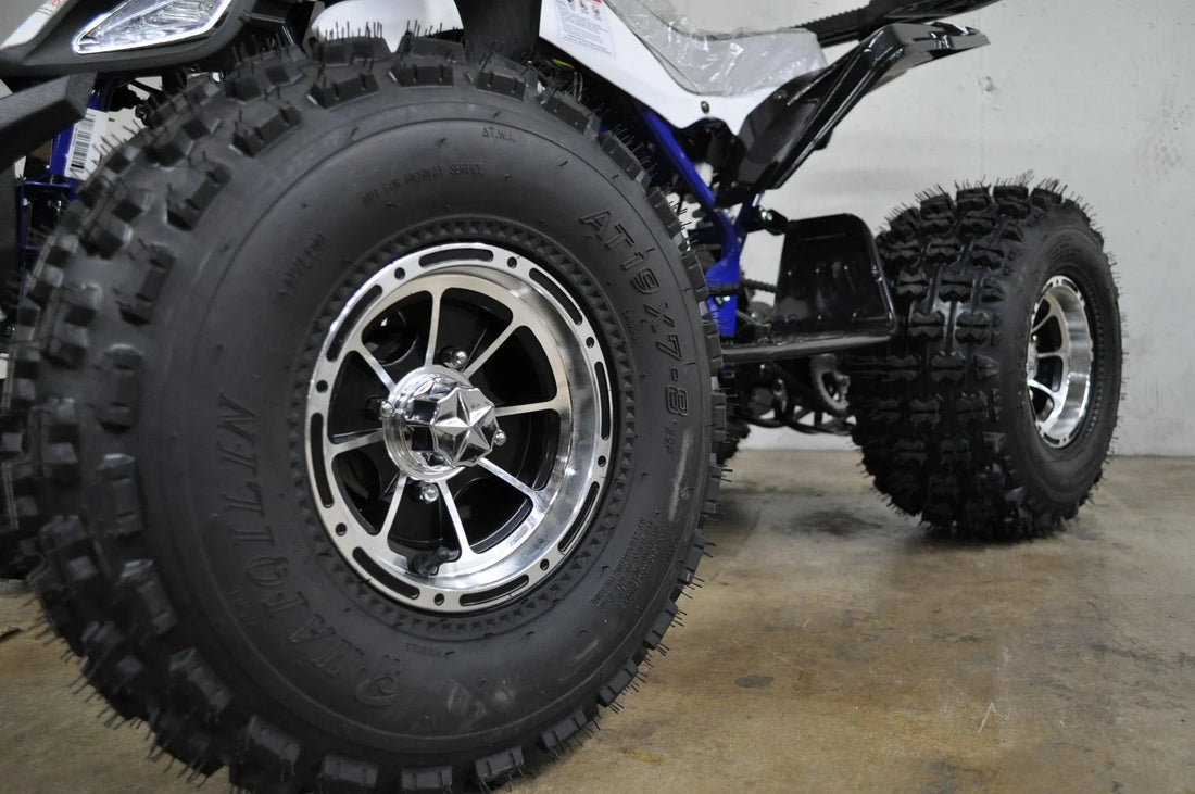 Close-up of ATV with knobby off-road tires and alloy rims on concrete floor