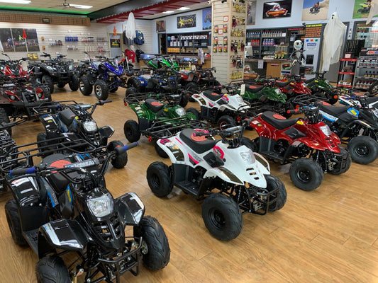 Showroom with various youth and adult ATVs in multiple colors on display