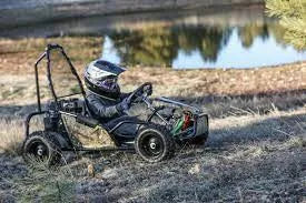 Person in helmet driving go-kart off-road near a pond, outdoor powersports vehicle