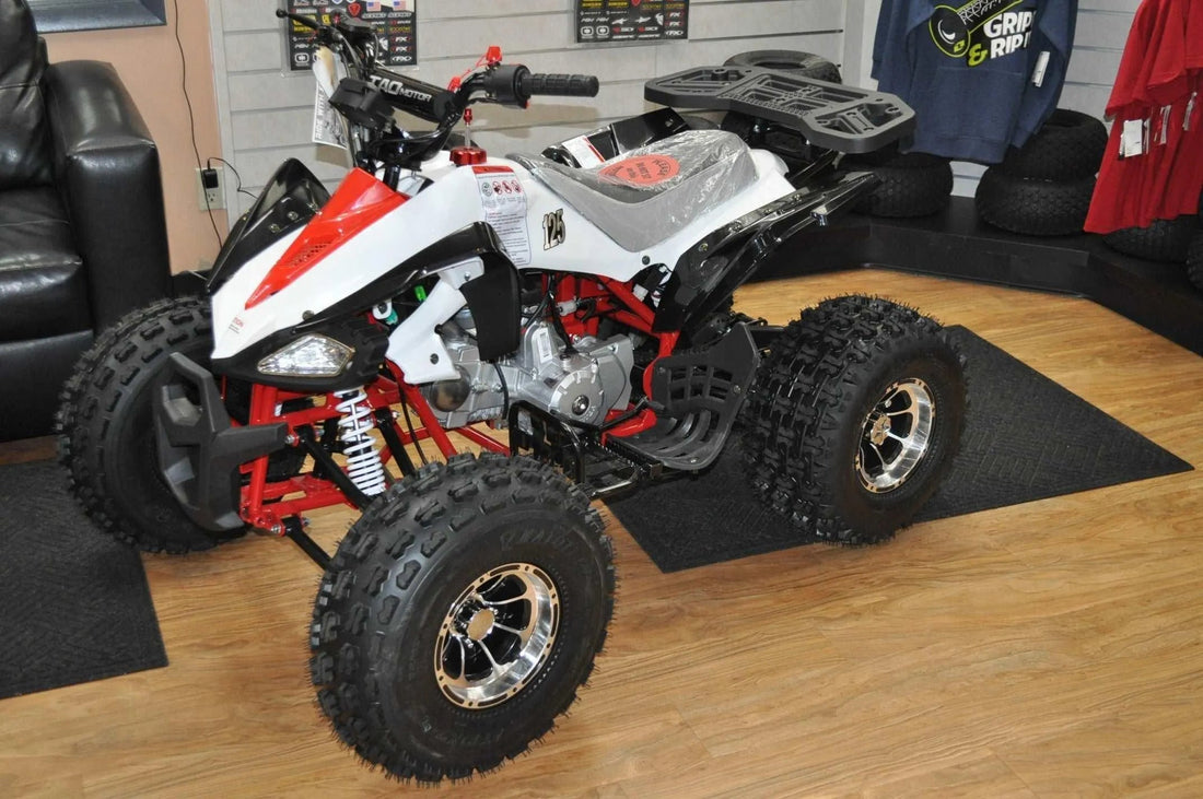 Youth ATV quad bike with off-road tires and sporty white and red body on showroom floor