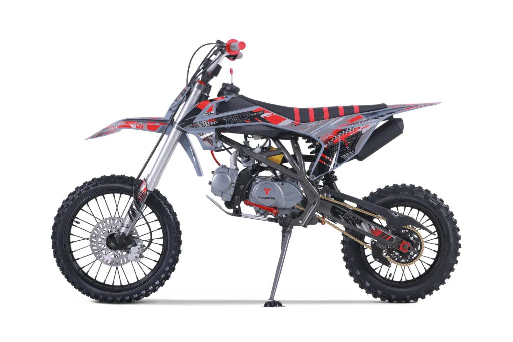 Red and black youth dirt bike with rugged tires and sporty graphics on white background