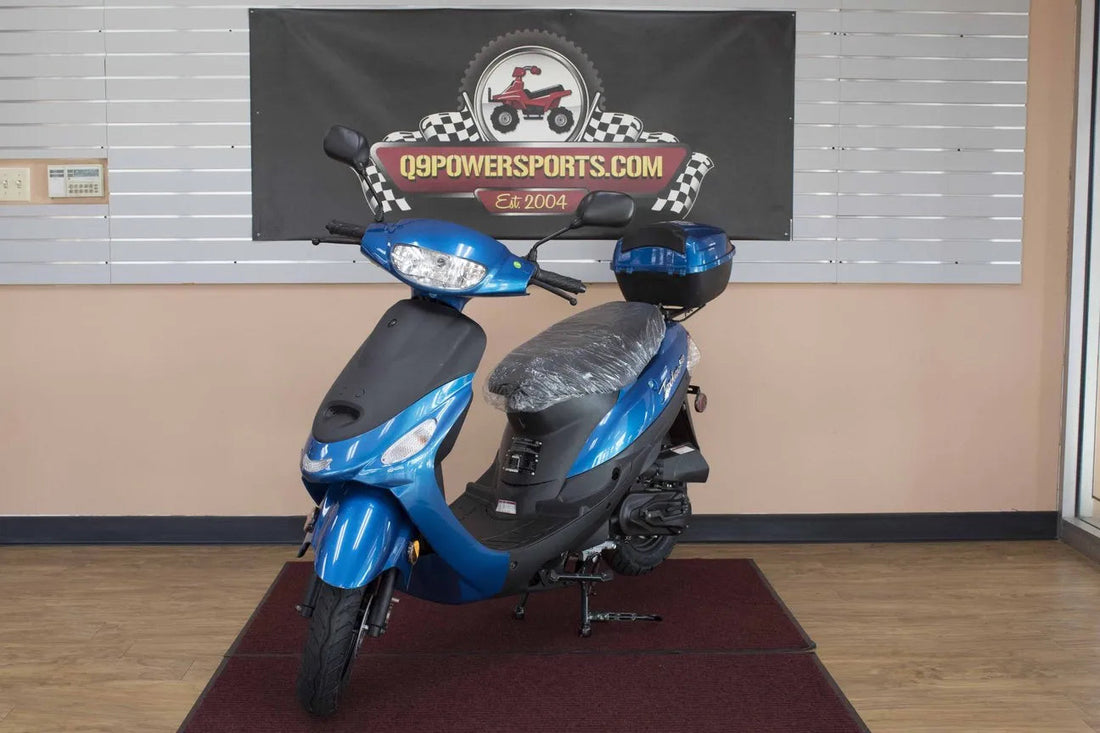 Blue motor scooter with rear storage box on showroom floor, front view indoors