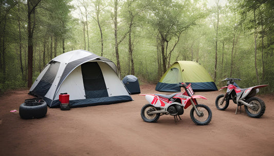 Two off-road dirt bikes parked at a forest campsite with tents on a dirt clearing