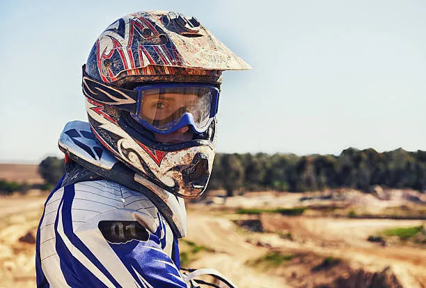 Dirt bike rider wearing a motocross helmet and goggles on an outdoor off-road track