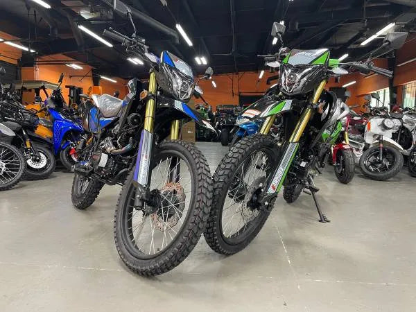 Dual sport dirt bikes with off-road tires displayed in a showroom with other power sports vehicles.