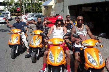 Group of men riding orange scooters outdoors on a sunny street