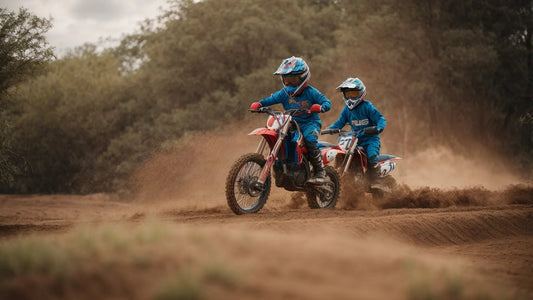 Two kids riding dirt bikes on a sandy outdoor trail, wearing blue motocross gear and helmets