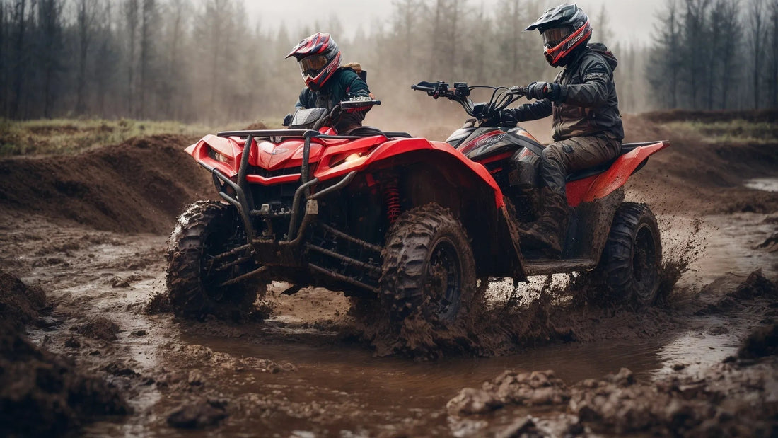 Two riders on red ATVs drive through muddy off-road terrain in a forested area.