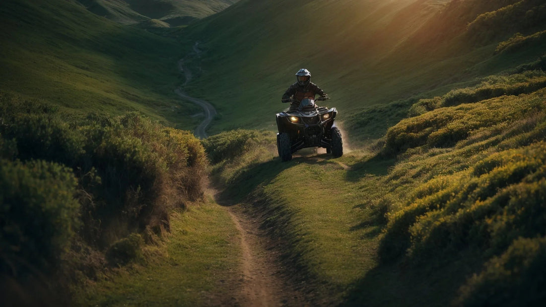 Rider driving ATV on dirt trail through green hills at sunset