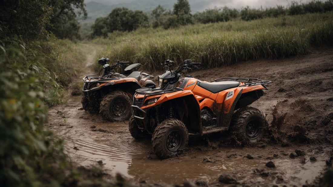 Two orange ATVs parked on a muddy off-road trail surrounded by grassy fields.