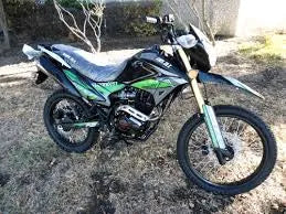Green and black dirt bike parked outdoors on grass, off-road motorcycle for adults