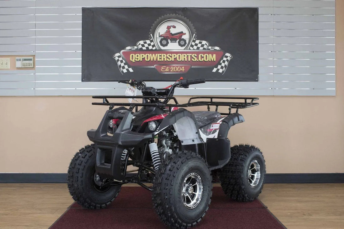 Black and red youth ATV with rugged tires on display indoors, parked on a maroon mat.