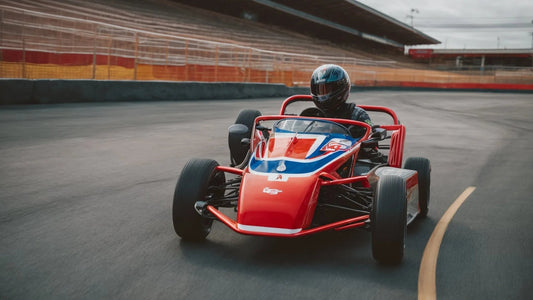 Person driving a red and blue go-kart on a racetrack, wearing a helmet
