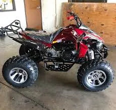 Red four-wheeler ATV with large off-road tires in a garage setting