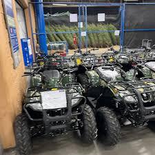 Multiple ATVs lined up indoors on showroom floor, ready for sale