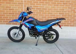 Blue 250cc dual sport motorcycle parked outside, Q9 PowerSports USA, brick wall background
