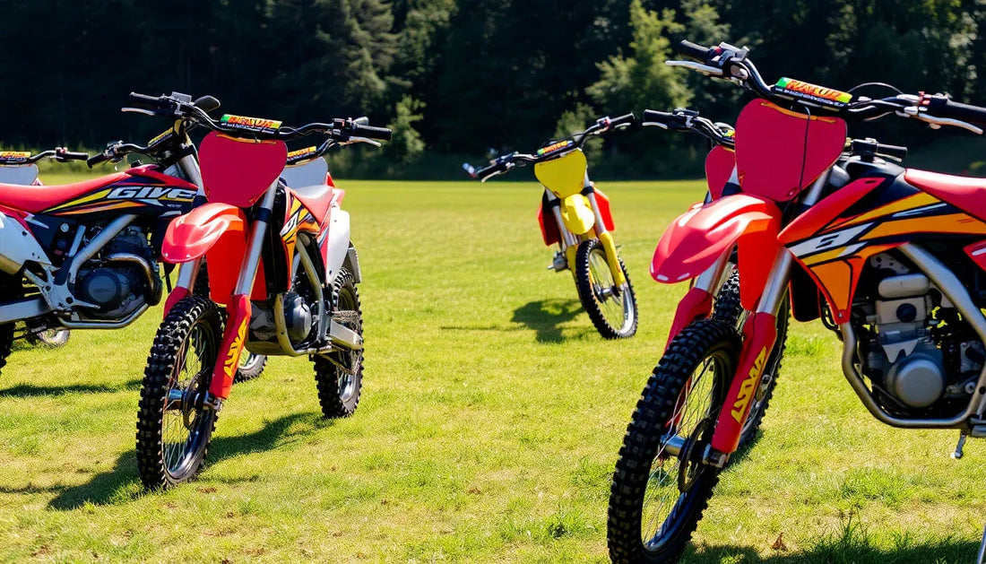 Colorful dirt bikes parked on green grass field with trees in the background