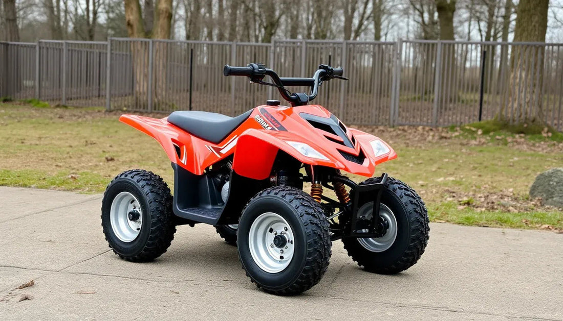 Youth red ATV with rugged tires parked outdoors on concrete by a fence and trees