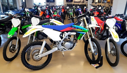 Dirt bikes with colorful graphics displayed in a showroom, off-road motorcycles for sale