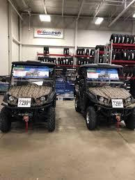 Camo utility vehicles for sale inside a showroom with tire displays in the background