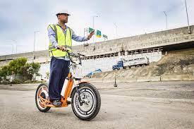 Worker riding orange electric fleet scooter on construction site, Q9 PowerSports USA