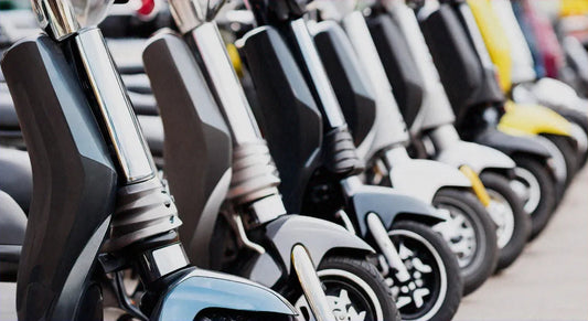 Row of modern scooters parked outdoors, close-up on front wheels and forks