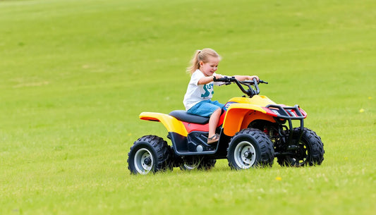 Child riding yellow and red ATV on grassy field