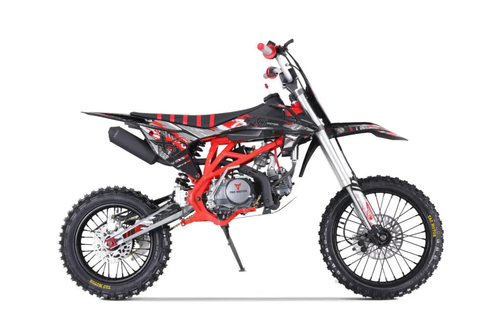 Black and red dirt bike with off-road tires and sporty graphics, side view on white background.