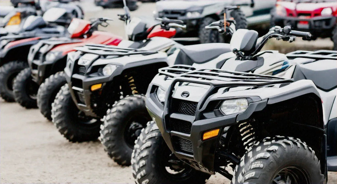 Row of all-terrain vehicles (ATVs) parked outdoors, showcasing rugged tires and off-road design.