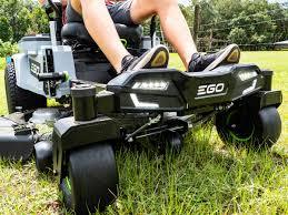 Battery-powered zero turn riding mower on grass, close-up of wheels and pedals outdoors