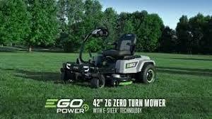 Electric zero-turn riding mower with e-steer on grass, trees in background.