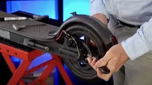 Technician repairing rear wheel and brake of electric scooter on workbench